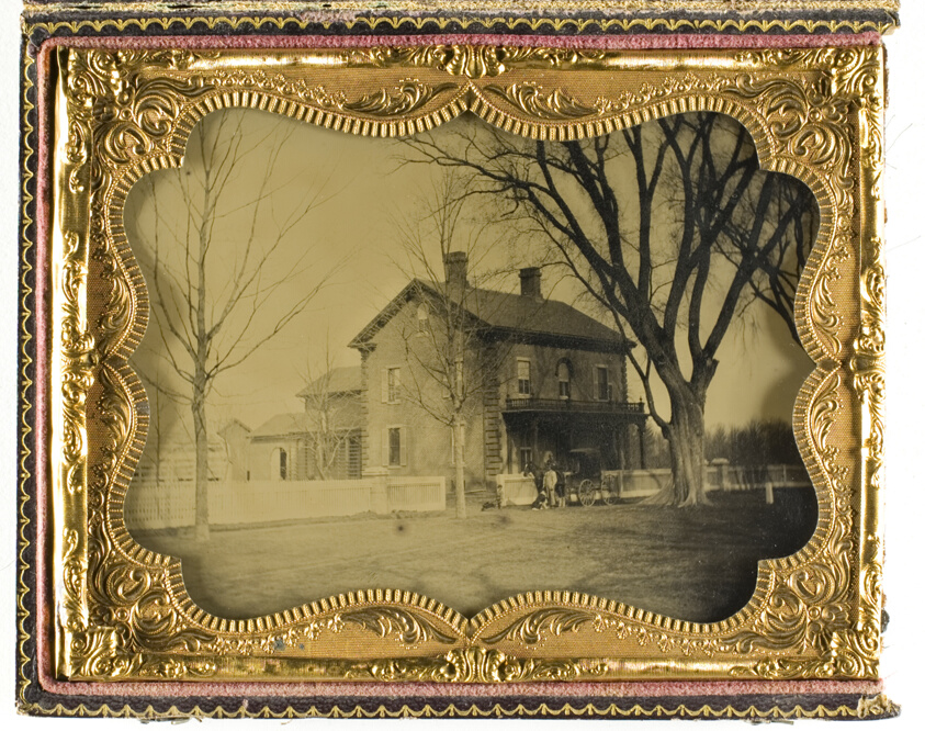 Artist unknown — Two and a Half Story Brick Country House with Outbuildings with Ornate Porch and Picket Fence