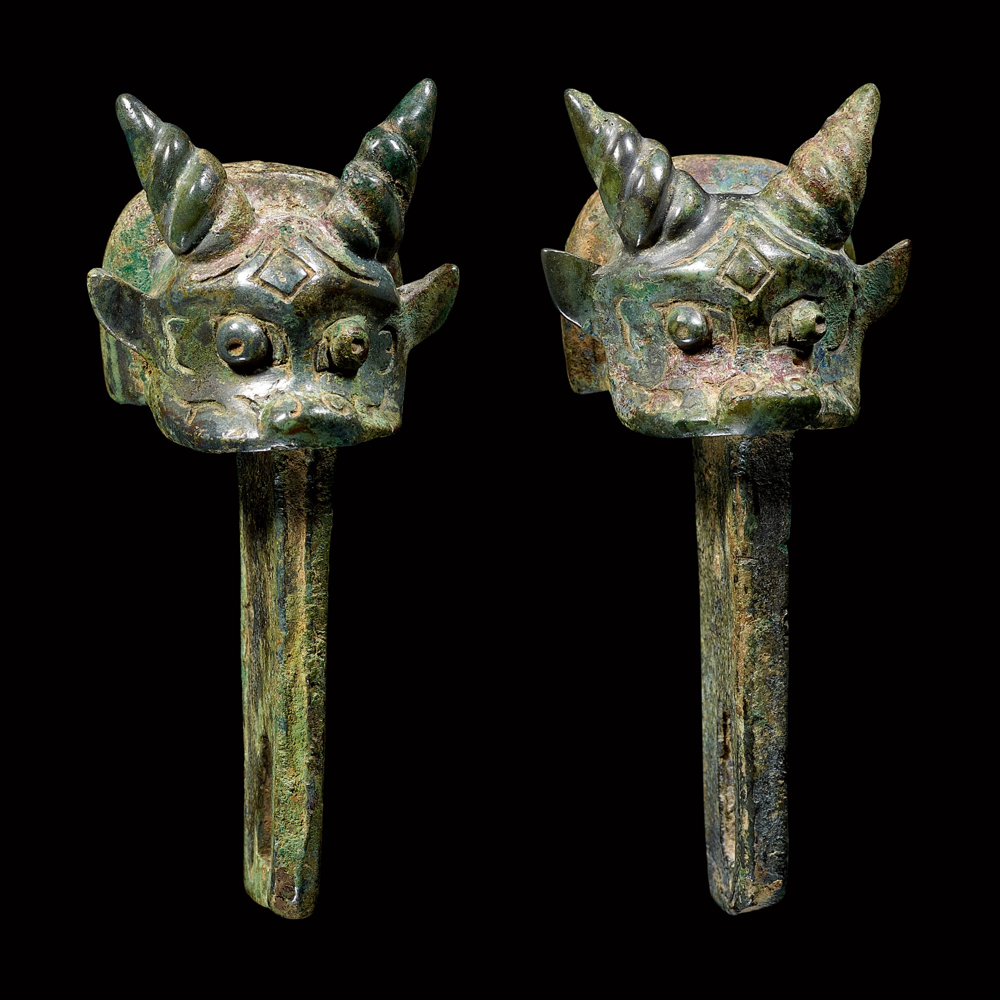 A pair of archaic bronze 'ox' linchpins — 商晚期至西周早期 青銅牛首車轄一對