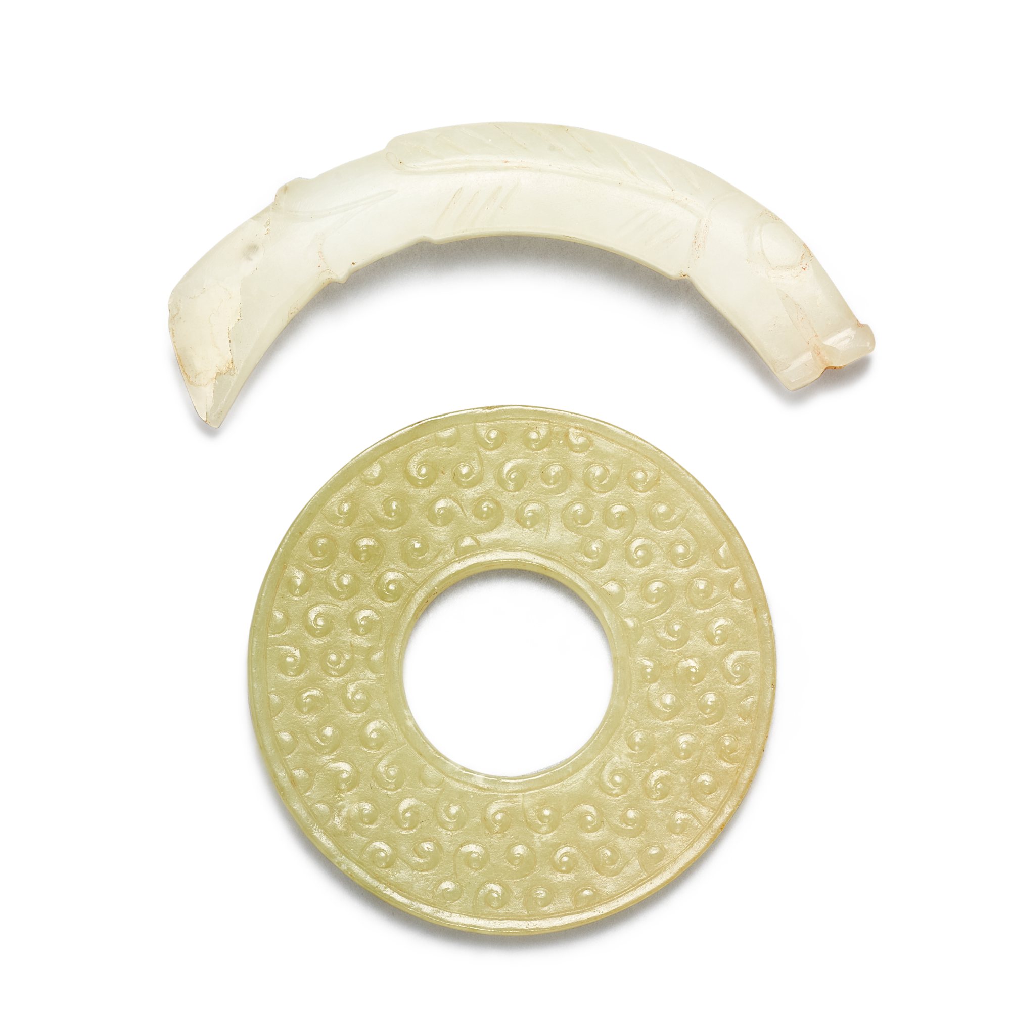 A celadon jade bi disc and a white jade ‘fish’ pendant, — A celadon jade bi disc and a white jade ‘fish’ pendant, Qing dynasty or earlier 清或更早 青玉穀紋環 及 白玉魚形璜