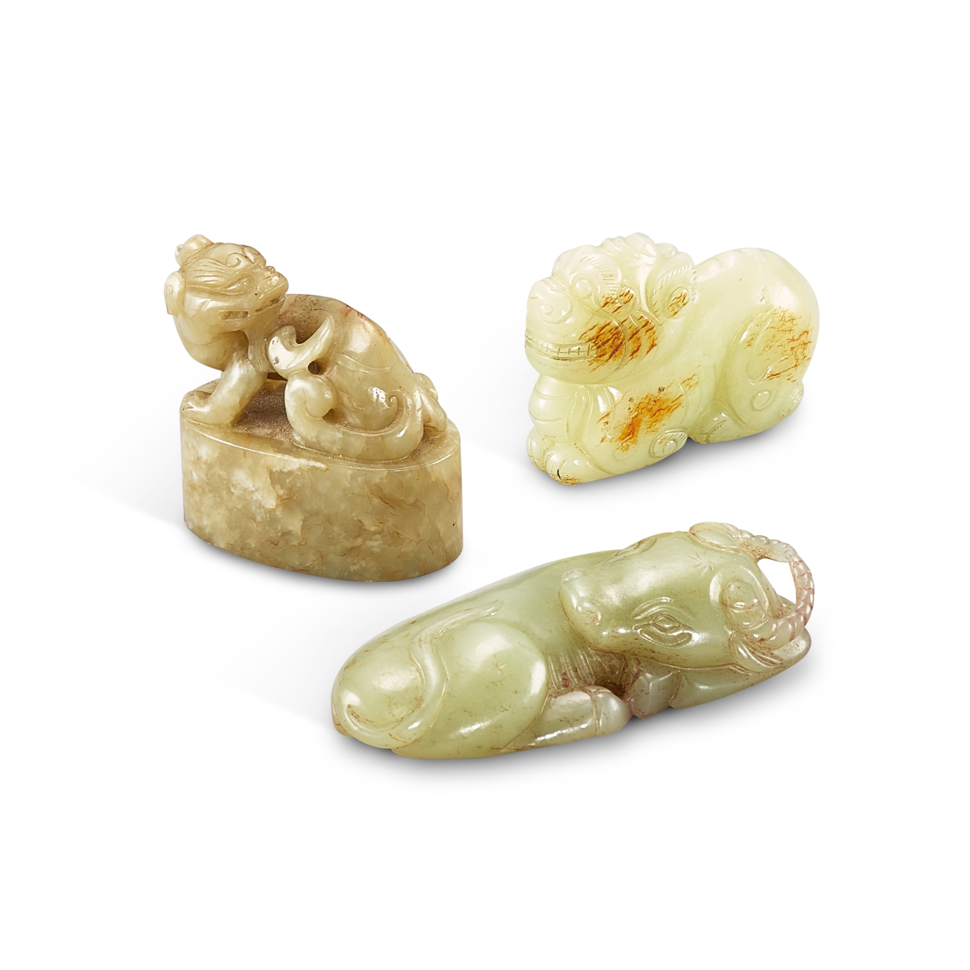 Three celadon and russet jade 'animal' carvings, — Three celadon and russet jade 'animal' carvings, Qing dynasty, 18th - 19th century 清十八至十九世紀 青玉雕臥牛、瑞獅及辟邪鈕印章
