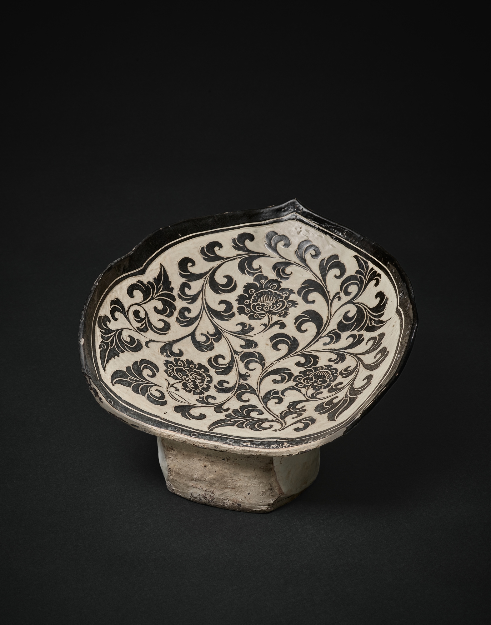 A superb and very rare Cizhou sgraffiato 'peony' pillow, — 北宋　磁州窰白地黑花纏枝牡丹紋如意形枕