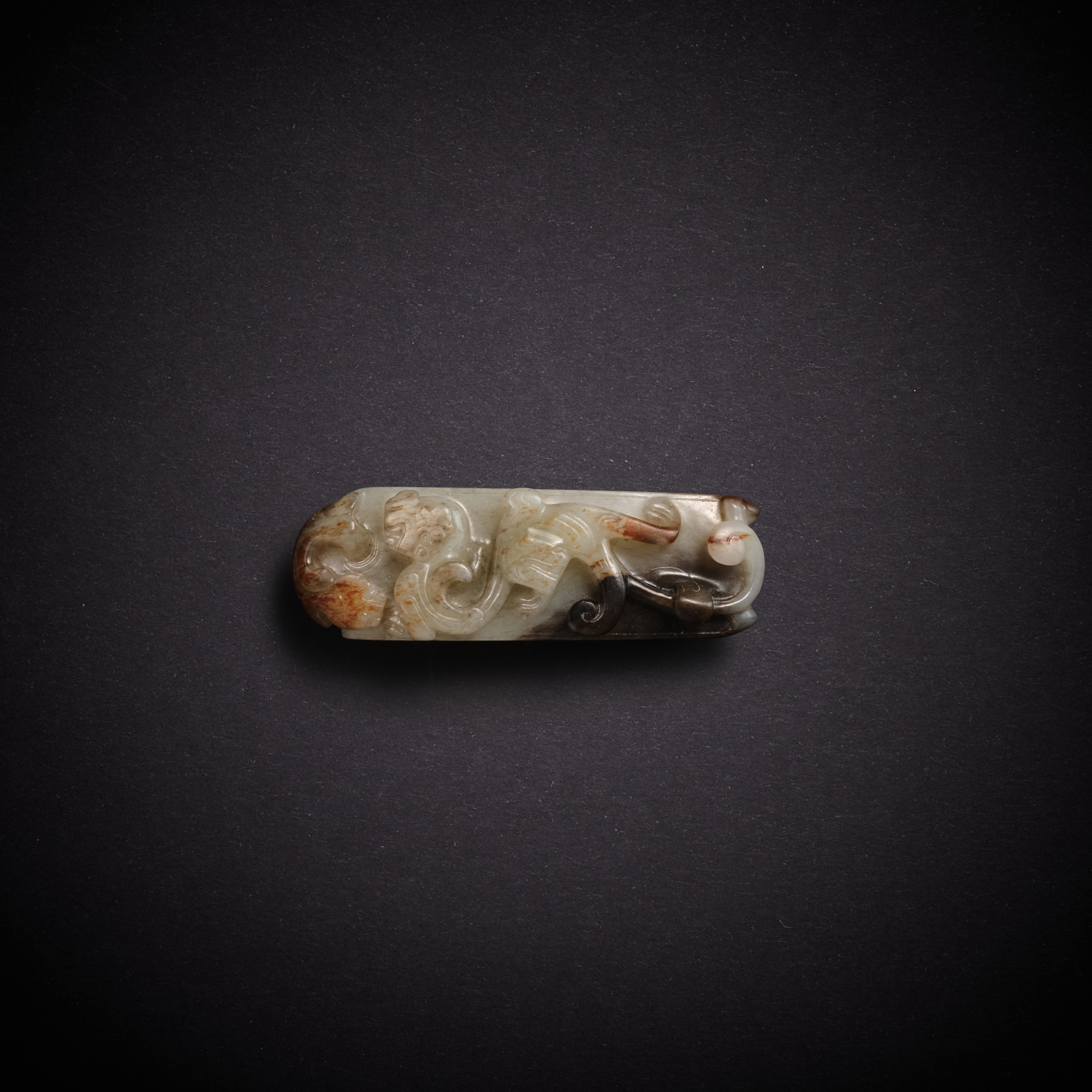 A greyish-white jade 'tiger' scabbard slide — 漢 灰白玉虎紋劍璏