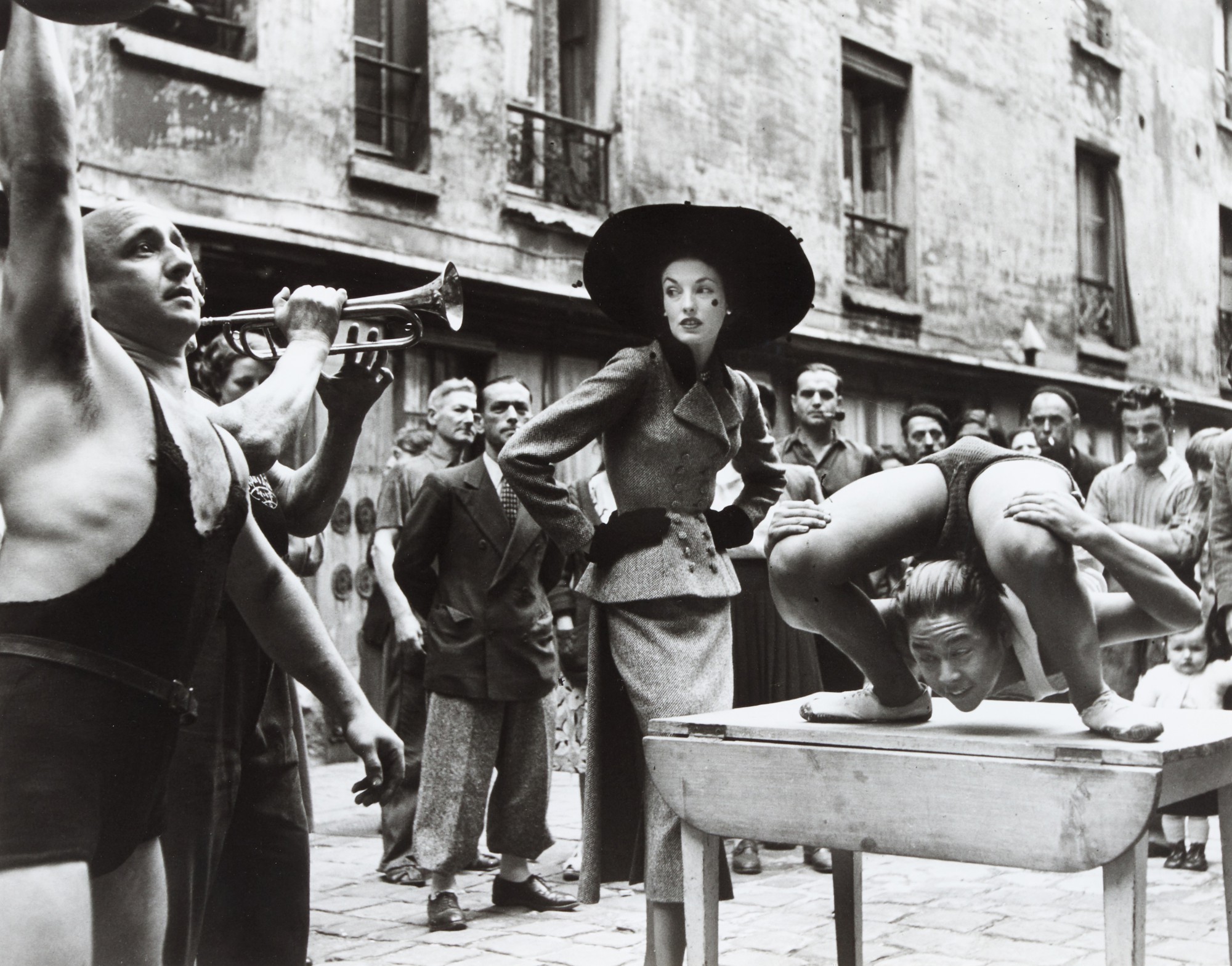 'Elise Daniels with street performers, Suit by Balenciaga, Le Marais, Paris', August 1948