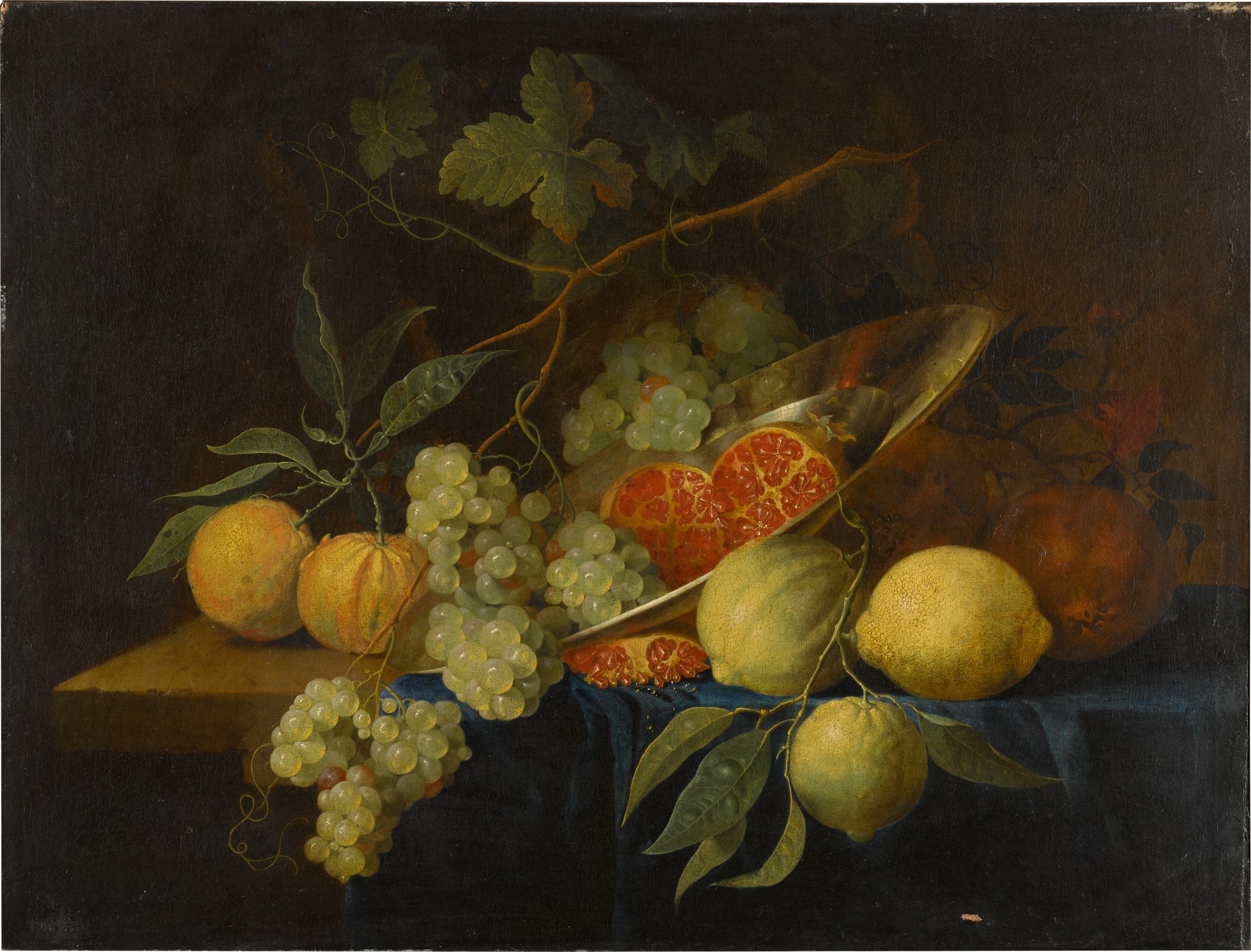 Unknown — Still life with pomegranates in a pewter dish, with lemons, oranges and grapes all on a draped stone ledge