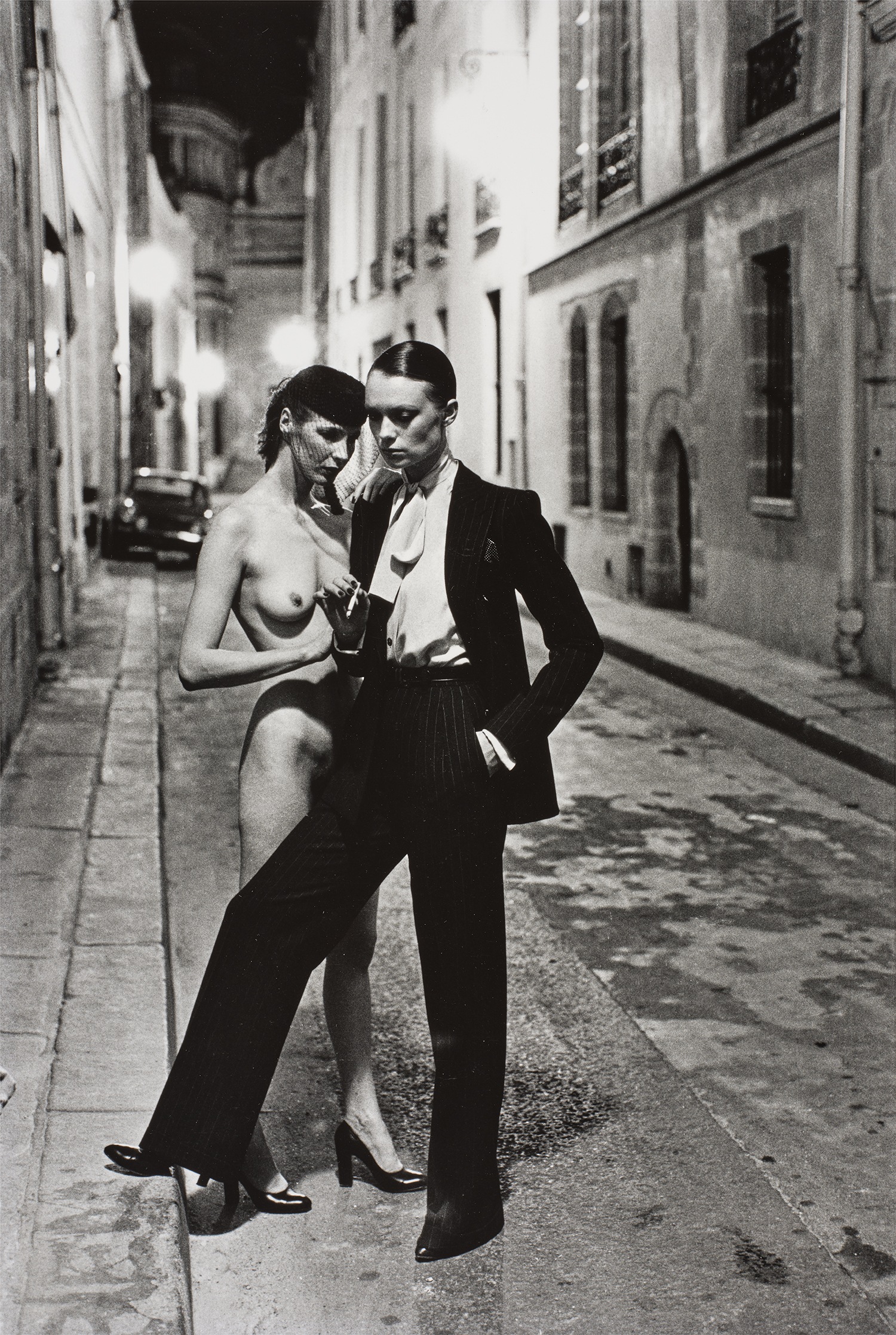 Helmut Newton — Yves St. Laurent's Man's Suit and Model Wearing Madame Paulette's Creation, Rue Aubriot, Paris 4ème ardt., Summer