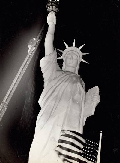 Man climbs 85-foot ladder to secure torch on the plastic Statue of Liberty erected at Times Square for the Sixth War Loan Drive, New York, November 30