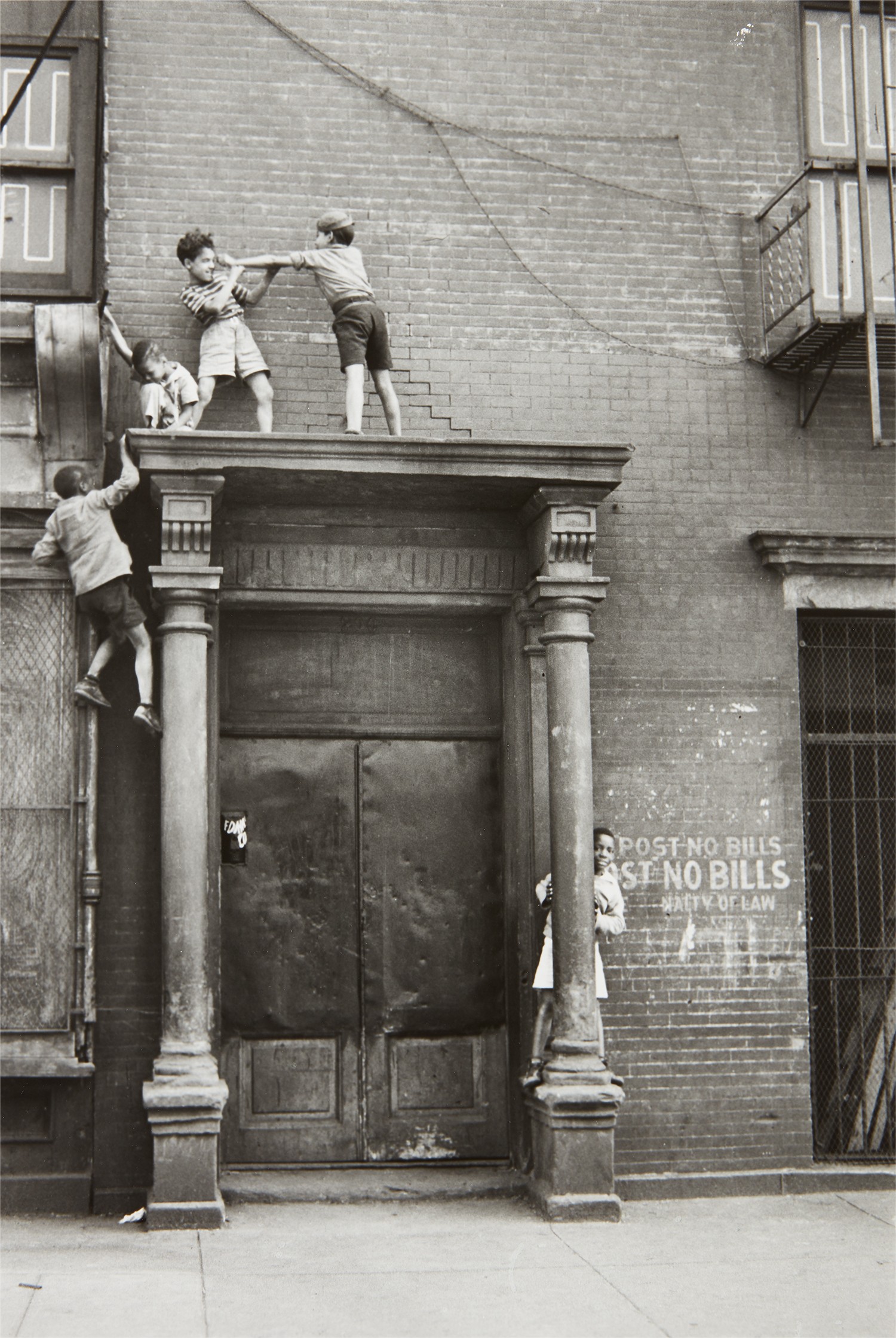 Helen Levitt — N.Y.C. (boys playing over doorway)