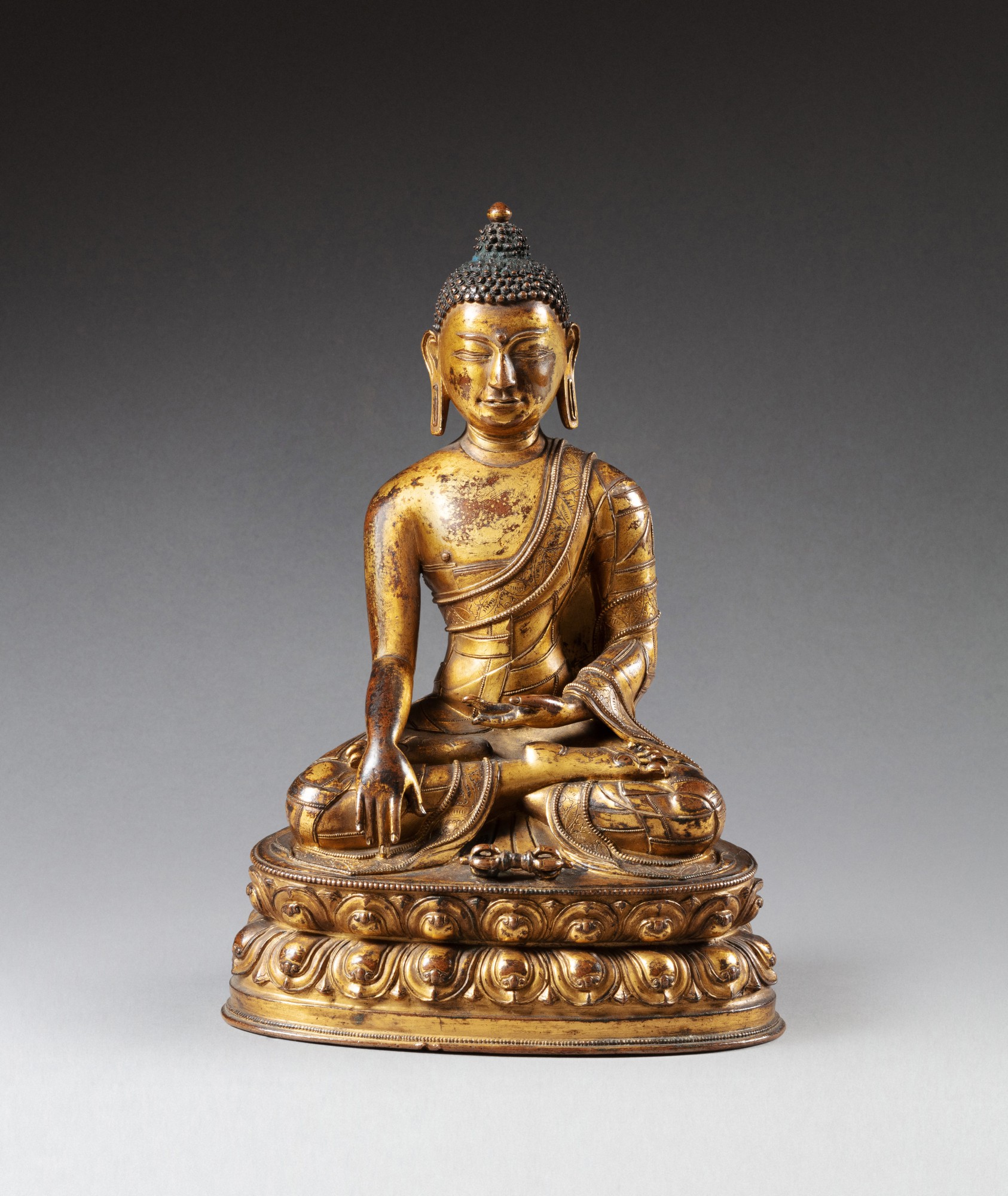 A gilt-copper alloy figure of a Buddha — 西藏 十五至十六世紀 鎏金銅合金佛坐像
