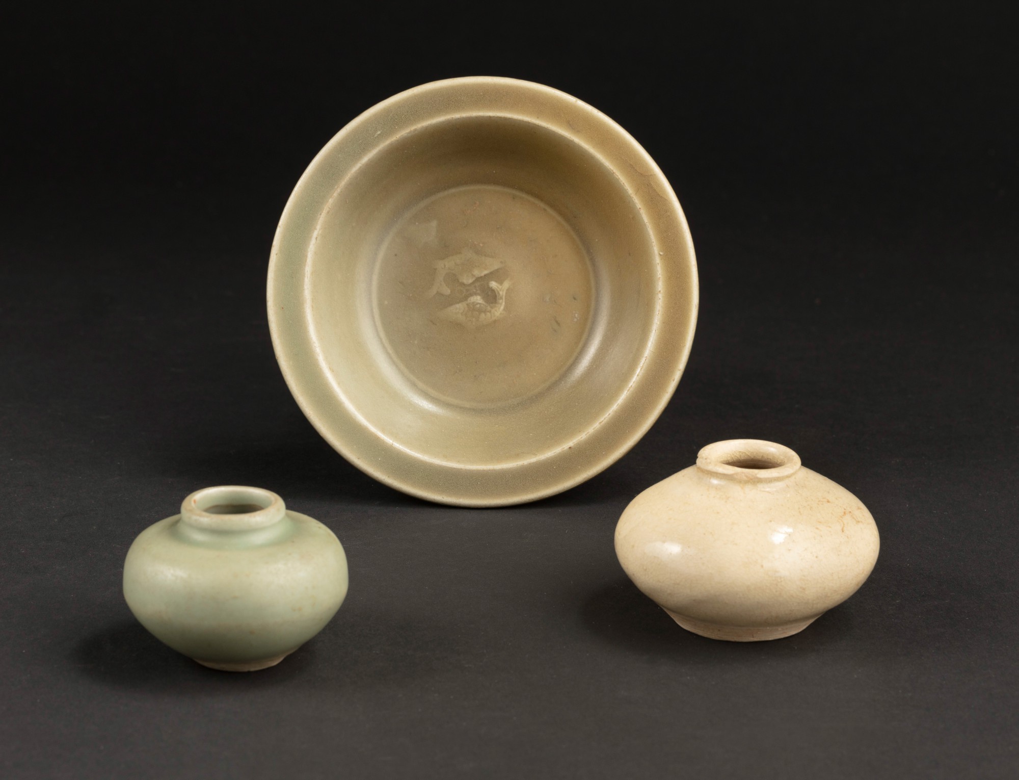 A Longquan celadon dish and two jarlets — 宋及明 龍泉窰印雙魚折沿盤、青釉罐及白釉罐一組三件