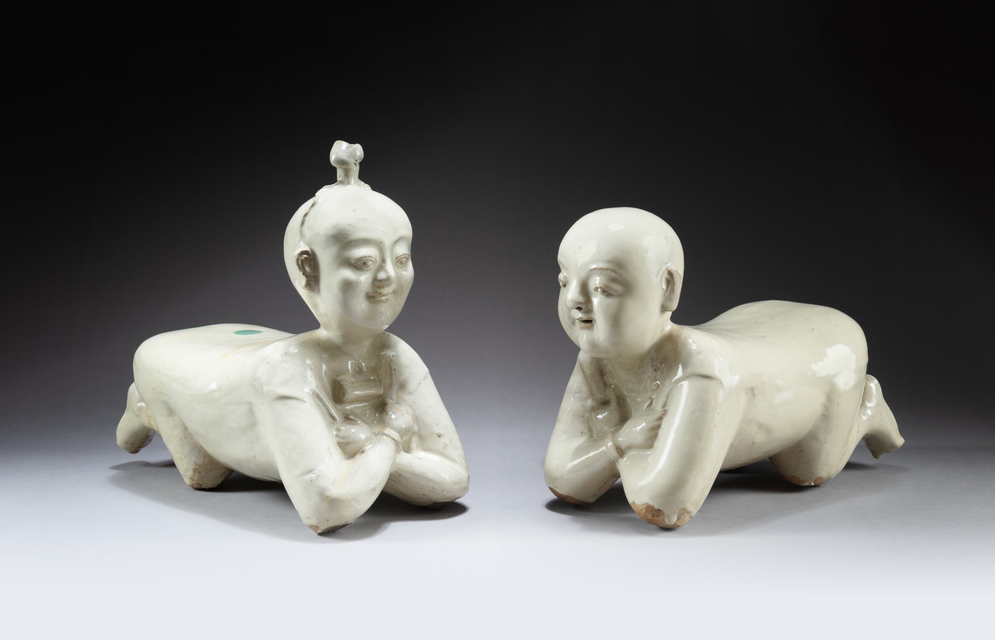 Two cream-glazed 'lying child' pillows