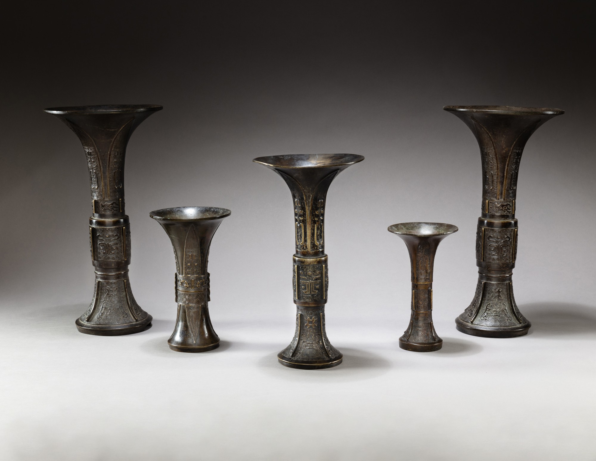 A garniture of five bronze altar archaistic beaker vases, gu — 明及清 十六至十八世紀 銅出㦸花觚一組五件