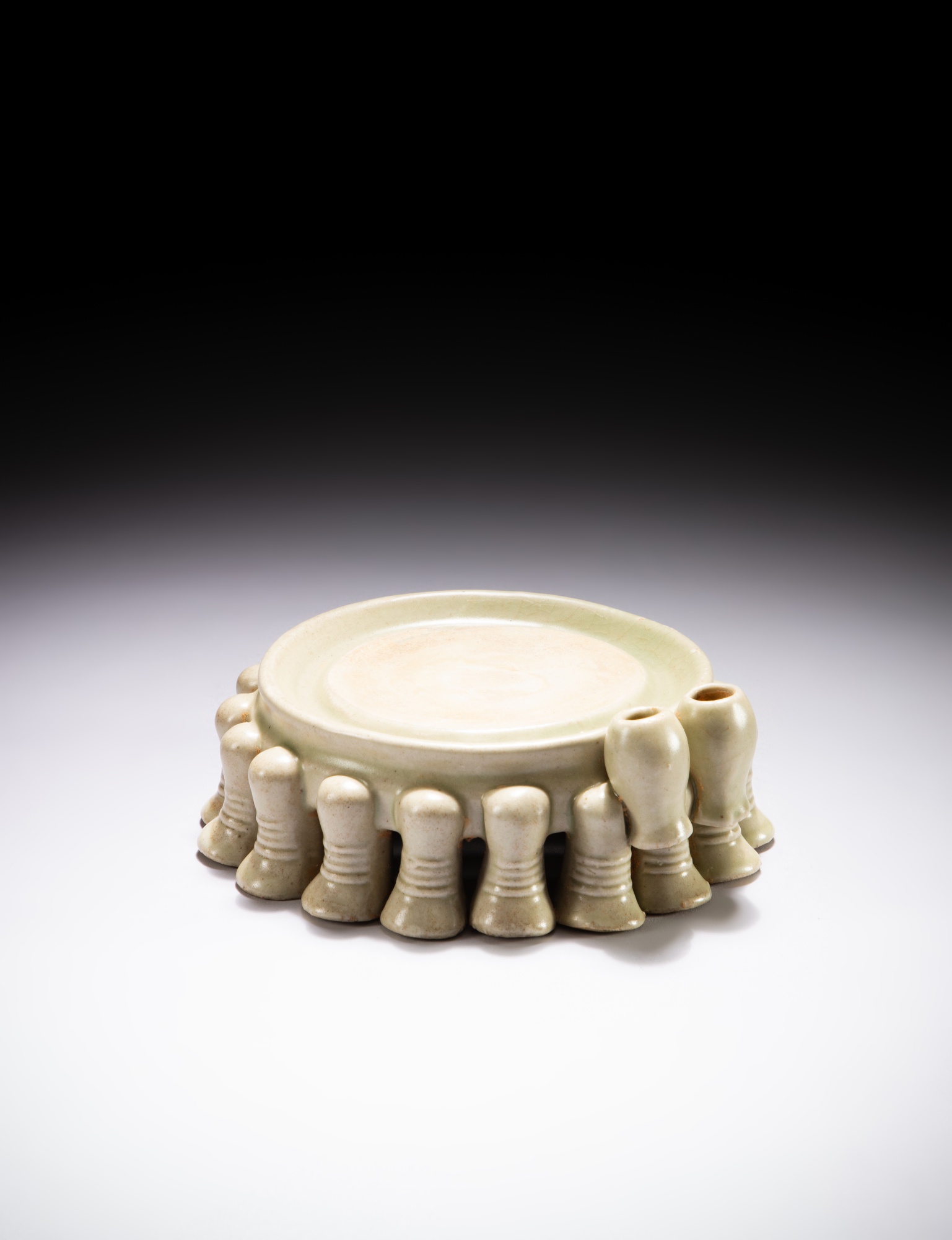 A circular bluish white glazed ‘elephant’ ink stone — 唐 白釉象足陶圓硯