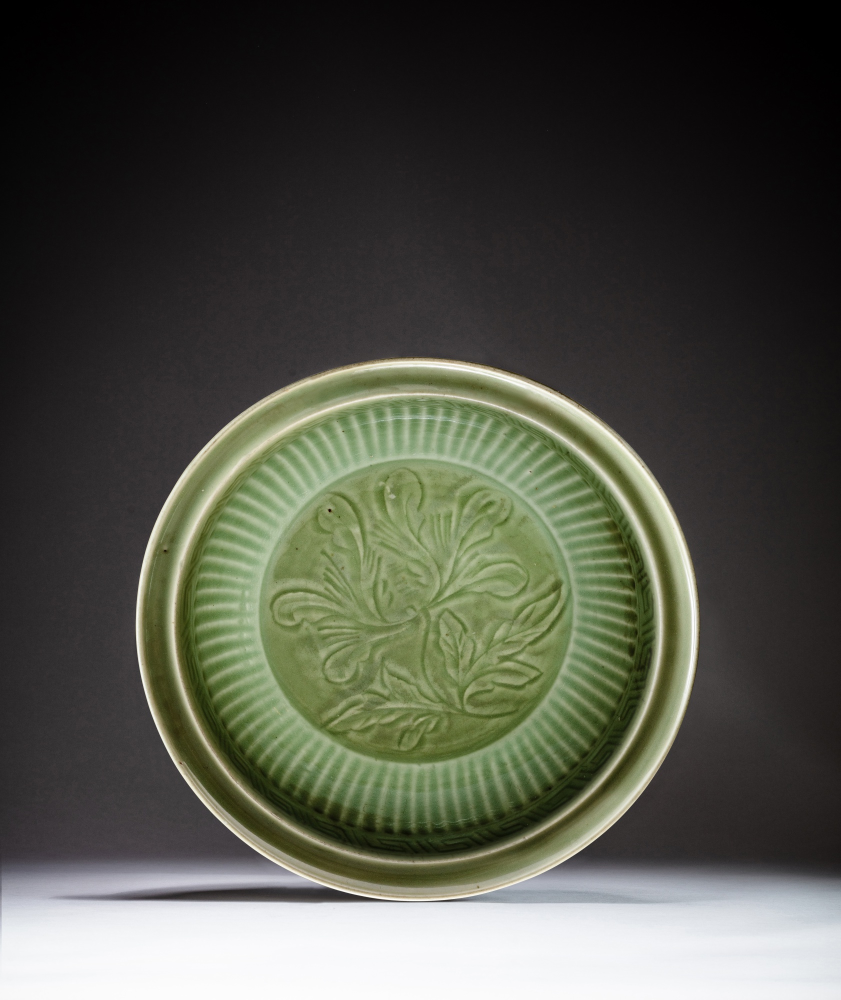 A flutted 'Longquan' celadon-glazed 'flower' charger — 元 龍泉窰青釉花卉紋折沿大盤