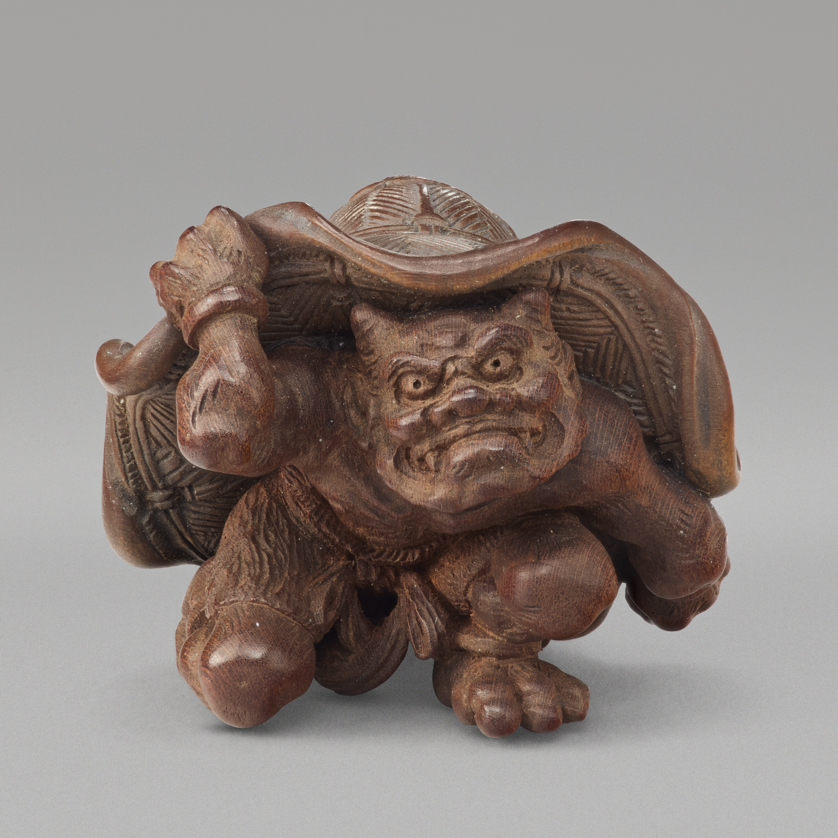 A Carved Wood Netsuke Miniature Sculpture Of Oni Under Hat — SHOWA PERIOD (20TH CENTURY), SIGNED SOSUI (OUCHI SOSUI; 1911-1972)