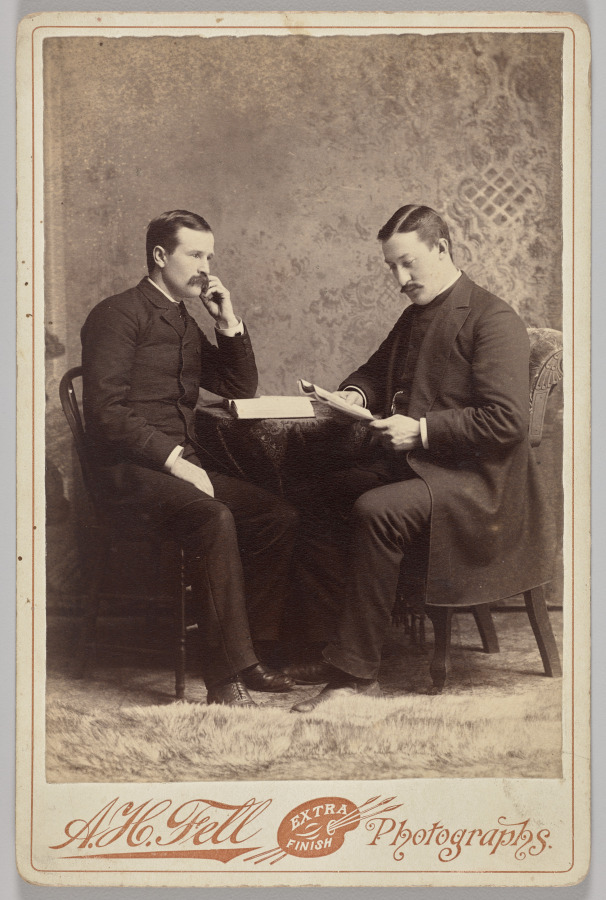 A.H. Fell — Untitled (seated portrait of two men, one with a book, the other reading a magazine)